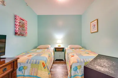 two beds in a room with a tv and a table at Gulf Coast Getaway with Balcony and Resort Amenities! in Panama City Beach