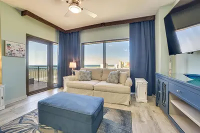 a living room with a couch and a tv at Breezy Panama City Beach Condo with Private Balcony! in Panama City Beach