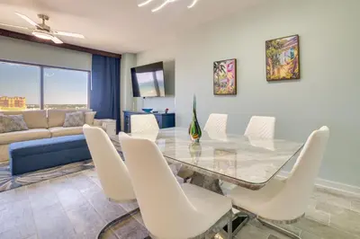 a dining room with a glass table and white chairs at Breezy Panama City Beach Condo with Private Balcony! in Panama City Beach