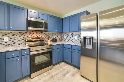 a blue kitchen with stainless steel appliances and blue cabinets at Breezy Panama City Beach Condo with Private Balcony! in Panama City Beach
