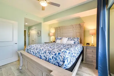 a bedroom with a large bed with a wooden headboard at Breezy Panama City Beach Condo with Private Balcony! in Panama City Beach