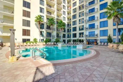 a swimming pool in front of a large apartment building at Breezy Panama City Beach Condo with Private Balcony! in Panama City Beach