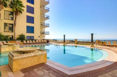 a swimming pool in a hotel with the ocean in the background at Breezy Panama City Beach Condo with Private Balcony! in Panama City Beach