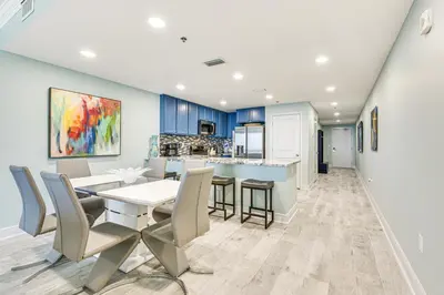 a kitchen and dining room with blue cabinets and a table and chairs at Panama City Beachfront Condo with Breathtaking Views in Panama City Beach