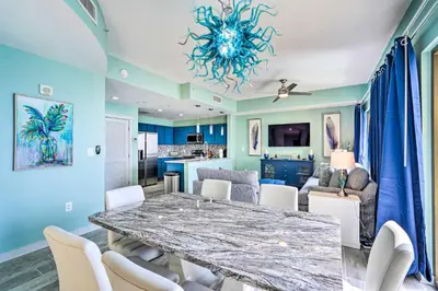 a dining room and living room with a table and chairs at Chic Panama City Beach Condo with Pool and Gulf Views in Panama City Beach