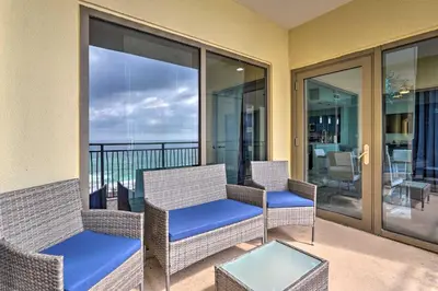 a balcony with wicker chairs and a table at Chic Panama City Beach Condo with Pool and Gulf Views in Panama City Beach