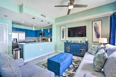 a living room with blue walls and a blue couch at Chic Panama City Beach Condo with Pool and Gulf Views in Panama City Beach