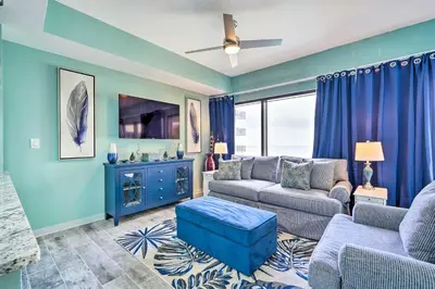 a living room with a couch and a tv at Chic Panama City Beach Condo with Pool and Gulf Views in Panama City Beach