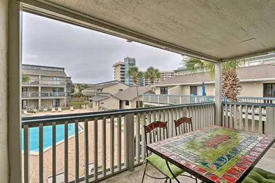 a balcony with a table and chairs and a view of a pool at Convenient PCB Condo with Pool Access Walk to Beach in Panama City Beach