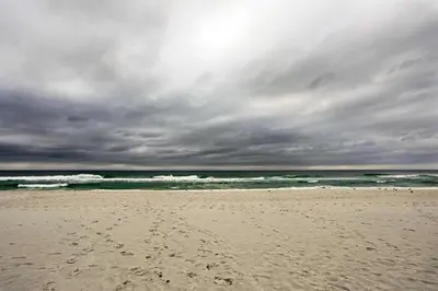 a beach with a cloudy sky and the ocean at Convenient PCB Condo with Pool Access Walk to Beach in Panama City Beach