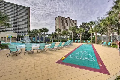 a pool with chairs and a table and a swimming pool at Oceanfront PCB Condo with Balcony and Pool Access! in Panama City Beach