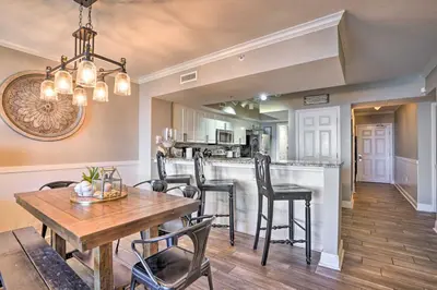 a dining room and kitchen with a wooden table and chairs at Oceanfront PCB Condo with Balcony and Pool Access! in Panama City Beach