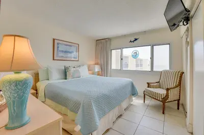 a bedroom with a bed and a chair and a window at Panama City Beach Retreat with Pool and Ocean Views! in Panama City Beach