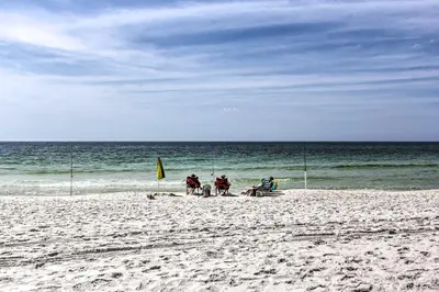 a group of people sitting on a beach at Panama City Beach Retreat with Pool and Ocean Views! in Panama City Beach