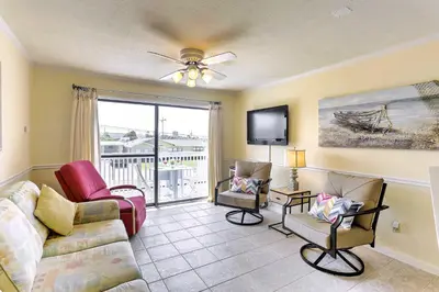 a living room with a couch and chairs and a tv at PCB Condo with Pool and Grill Access - Walk to Beach! in Panama City Beach