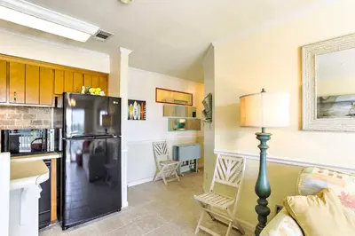 a kitchen with a black refrigerator in a living room at PCB Condo with Pool and Grill Access - Walk to Beach! in Panama City Beach