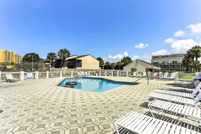 a swimming pool with lounge chairs and a poolvisorvisor at PCB Condo with Pool and Grill Access - Walk to Beach! in Panama City Beach