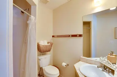 a bathroom with a toilet and a sink and a mirror at Cute PCB Condo by Lake Powell with Pool Access! in Panama City Beach