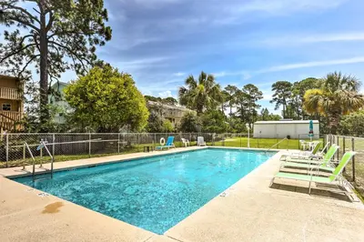 a swimming pool with chairs and a fence at Cute PCB Condo by Lake Powell with Pool Access! in Panama City Beach