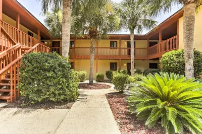 a resort building with palm trees and a walkway at Cute PCB Condo by Lake Powell with Pool Access! in Panama City Beach