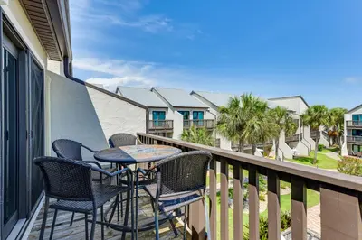 a patio with chairs and a table on a balcony at Seaside Panama City Beach Condo with Outdoor Pool! in Panama City Beach