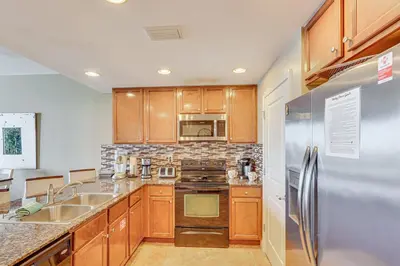 a kitchen with wooden cabinets and a stainless steel refrigerator at Beachfront Panama City Condo Walk to Pier Park! in Panama City Beach