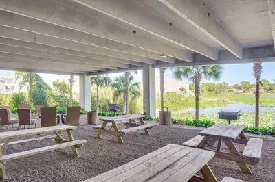 a picnic area with picnic tables and chairs and a lake at Beachfront Panama City Condo Walk to Pier Park! in Panama City Beach