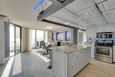 a kitchen with white cabinets and a table with chairs at Community Perks! Luxury Panama City Beach Condo in Panama City Beach