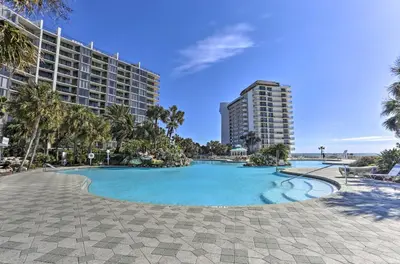 a swimming pool with palm trees and a building at Community Perks! Luxury Panama City Beach Condo in Panama City Beach