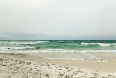 a sandy beach with waves in the ocean at Community Perks! Luxury Panama City Beach Condo in Panama City Beach