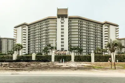 a large white building with palm trees in front of it at Community Perks! Luxury Panama City Beach Condo in Panama City Beach
