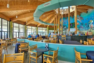 a restaurant with tables and chairs and a large aquarium at Community Perks! Luxury Panama City Beach Condo in Panama City Beach
