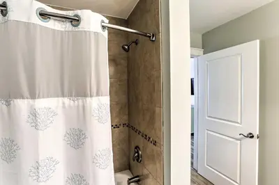 a bathroom with a shower with a white shower curtain at Coastal Florida Abode with Pool Access and Ocean Views in Panama City Beach