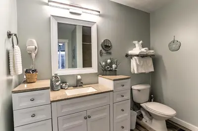 a bathroom with a sink and a toilet and a mirror at Coastal Florida Abode with Pool Access and Ocean Views in Panama City Beach
