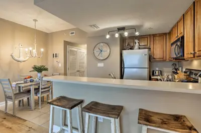 a kitchen and dining room with a counter and a refrigerator at Resort Pool, Gym and Hot Tub Beachfront PCB Condo! in Panama City Beach