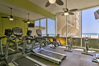 a gym with several tread machines in a room with windows at Oceanfront PCB Condo with Beach Access and 2 Pools in Panama City Beach