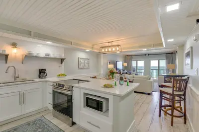 a kitchen with white cabinets and a living room at Oceanfront PCB Condo with Beach Access and 2 Pools in Panama City Beach