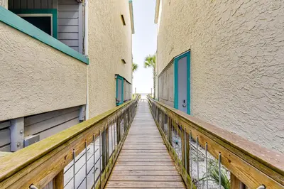 a wooden walkway between two buildings with blue doors at Oceanfront Panama City Beach Condo with Balcony! in Panama City Beach