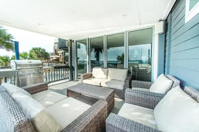 a patio with couches and a grill on a balcony at Klaus House 1 in Panama City Beach