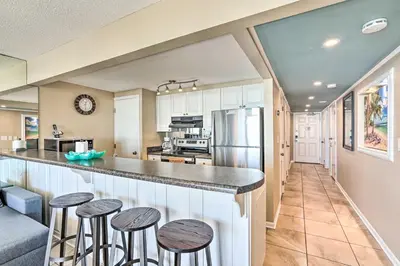 a kitchen with a counter and stools at a bar at Chic PCB Condo with Pool Access and Beachfront Balcony in Panama City Beach