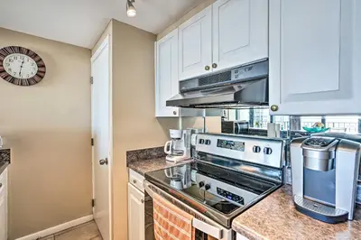 a kitchen with white cabinets and a stove top oven at Chic PCB Condo with Pool Access and Beachfront Balcony in Panama City Beach