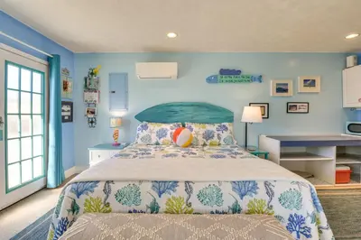 a bedroom with a bed with a blue wall at PCB Studio with Private Patio Steps to Beach! in Panama City Beach
