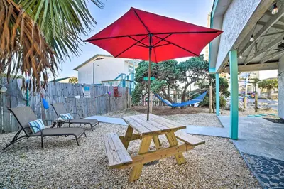 a picnic table with a red umbrella and a bench at PCB Studio with Private Patio Steps to Beach! in Panama City Beach