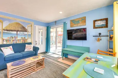 a living room with a blue couch and a table at PCB Studio with Private Patio Steps to Beach! in Panama City Beach