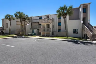 a parking lot in front of a building with palm trees at Sugar Beach C-17 (2/2) in Panama City Beach