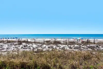 a beach with a fence and people in the ocean at Sugar Beach C-17 (2/2) in Panama City Beach