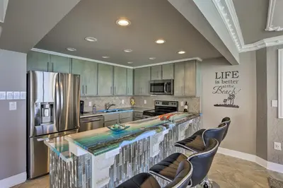 a kitchen with a large counter with chairs and a refrigerator at Panama City Beach Condo with Balcony and Ocean Views in Panama City Beach