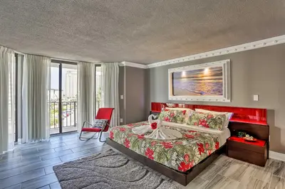 a bedroom with a bed and a red chair at Panama City Beach Condo with Balcony and Ocean Views in Panama City Beach