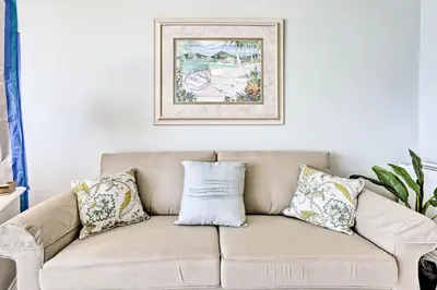 a couch with pillows and a picture on the wall at Bright PCB Condo with Gulf Views and Beach Access! in Panama City Beach