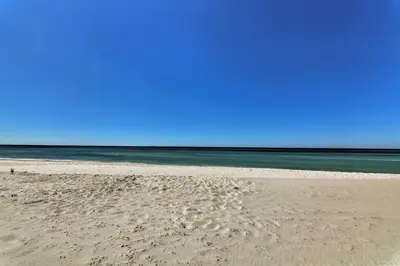 a sandy beach with the ocean in the background at Bright PCB Condo with Gulf Views and Beach Access! in Panama City Beach